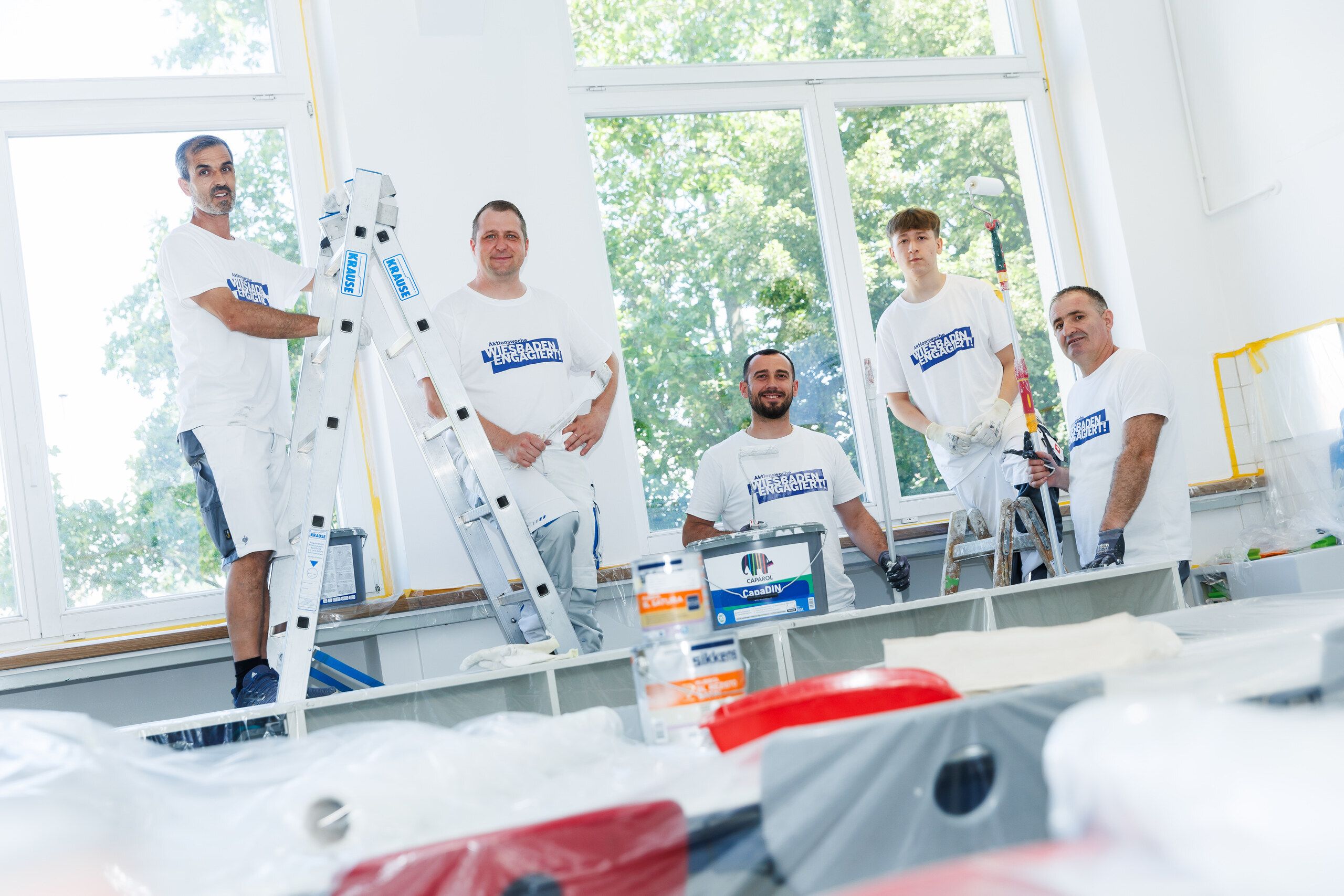 Das Team des Malerfachbetriebs Schünemann in Arbeitskleidung bei Malerarbeiten in einem hellen Raum